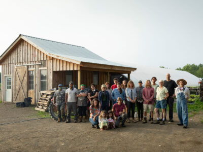 large group of farmers standing in front of a barn