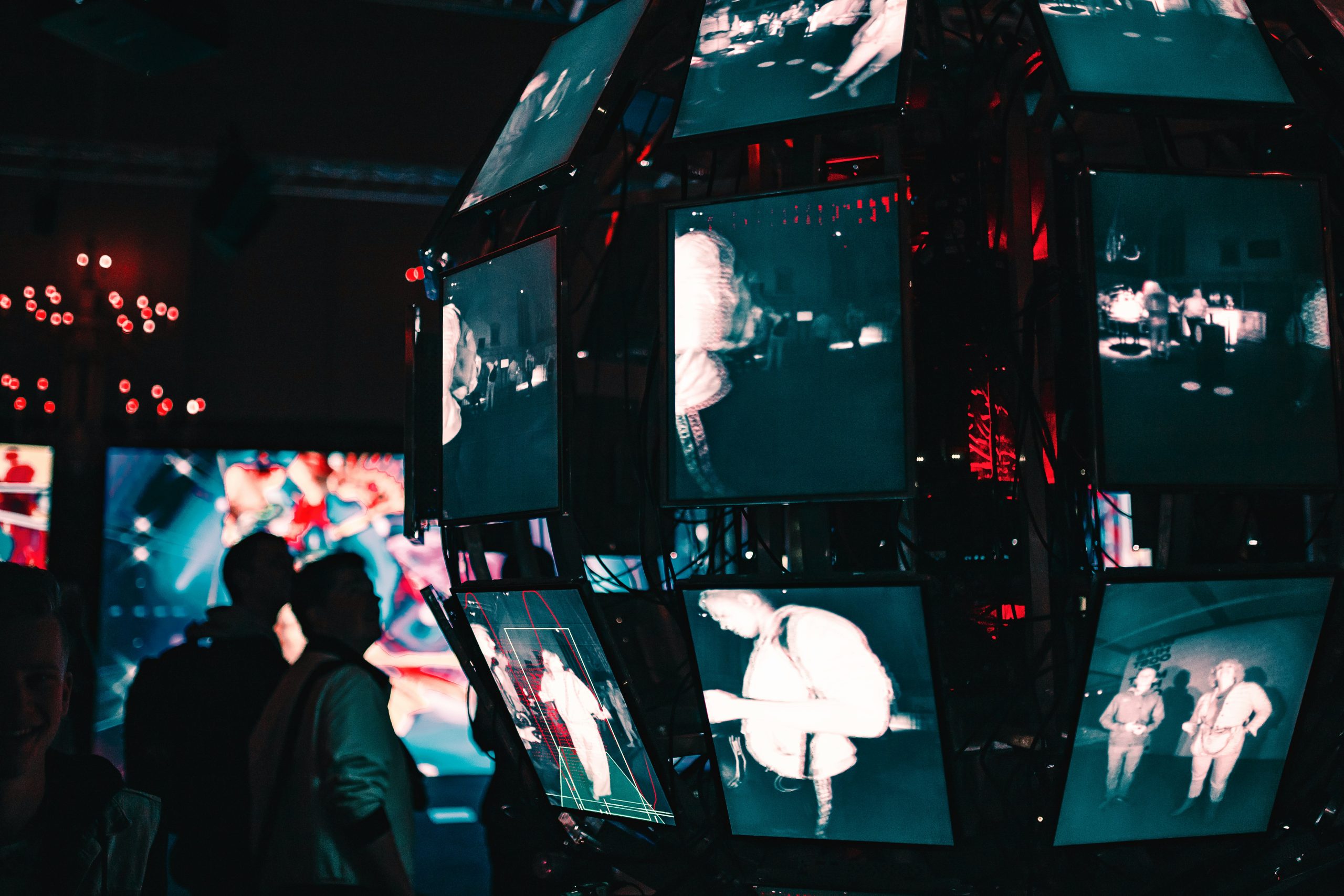 Photo of a group of people standing around a display of video screens