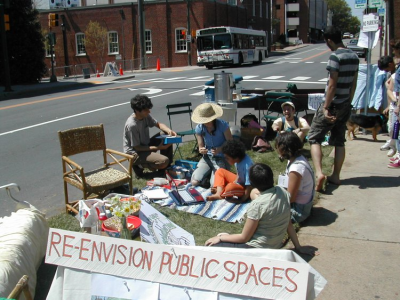 Picture of neighbors coming together with sign reading "re-envision public spaces"